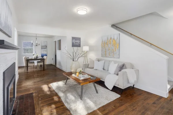 A modern white bathroom featuring a glass-enclosed shower with grey subway tiles, a pedestal sink, and a toilet, all in a clean, minimalist design.
