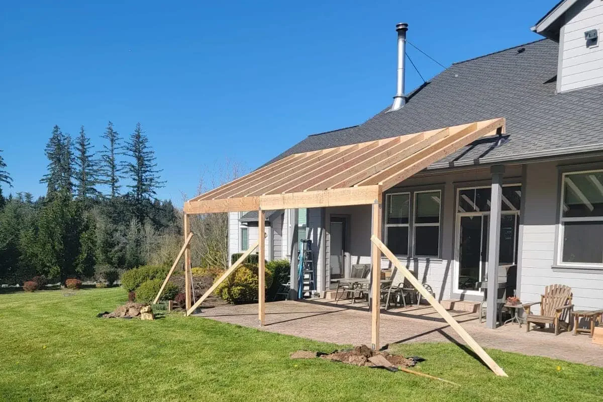 An open concept kitchen with a large island, white cabinets, and dark ceiling beams.