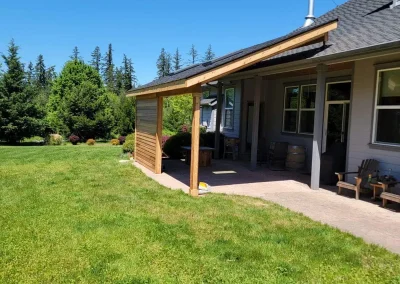 Newly constructed home addition in Seattle featuring a modern covered patio with a wooden privacy wall, seamlessly integrated with the existing home by top home addition contractors in Seattle.