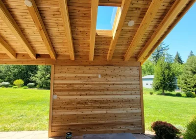Interior view of a Seattle home addition featuring a covered patio with a wooden slatted ceiling, skylight, and built-in lighting, designed by leading home addition contractors in Seattle