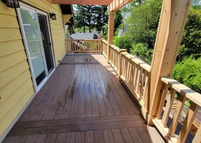 Spacious composite deck with a custom wooden pergola and decorative railing, attached to a yellow Seattle home. Expertly built by deck and patio contractors in Seattle for enhanced outdoor living and relaxation.