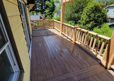 Elegant composite deck with a wooden pergola and custom railing, attached to a yellow home in Seattle. Expertly crafted by top deck and patio contractors in Seattle for a stylish outdoor living space.