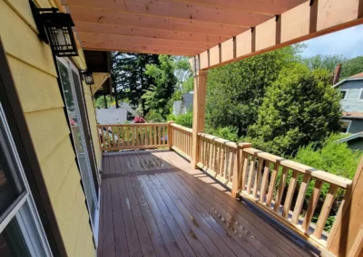 Elegant composite deck with a wooden pergola and custom railing, attached to a yellow home in Bellevue. Expertly crafted by top deck and patio contractors in Bellevue for a stylish outdoor living space.