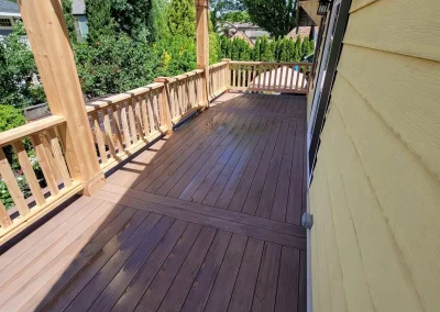 Spacious composite deck with a custom wooden pergola and decorative railing, attached to a yellow Seattle home. Expertly built by deck and patio contractors in Seattle for enhanced outdoor living.
