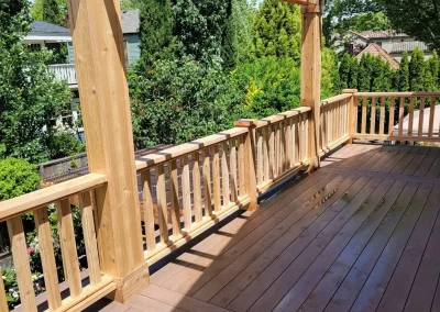 Beautiful wooden pergola over a spacious composite deck with custom railing, attached to a yellow home in Seattle. Built by expert deck and patio contractors in Seattle for enhanced outdoor living.
