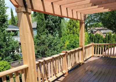 Beautiful wooden pergola over a spacious composite deck with custom railing, attached to a yellow home in Bellevue. Built by expert deck and patio contractors in Bellevue for enhanced outdoor living.