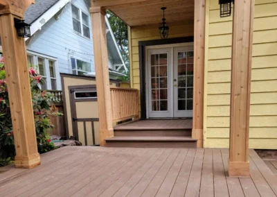 Custom-built composite deck with a wooden pergola and covered entryway, leading to French doors of a Bellevue home. Designed by expert deck and patio contractors in Bellevue for elegance and durability