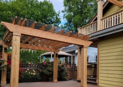 Custom-built wooden pergola with a transparent polycarbonate roof, set on a raised composite deck with wide stairs in a Bellevue backyard. Expertly designed by deck and patio contractors in Bellevue for enhanced outdoor living