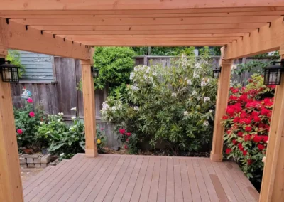 Beautiful wooden pergola with a transparent roof, built over a composite deck in a landscaped Bellevue backyard. Designed by expert patio and deck contractors in Bellevue for a stylish and functional outdoor space.
