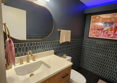 Seattle bathroom remodel featuring a modern wood vanity with a quartz countertop, gold fixtures, hexagonal tile backsplash, and ambient LED lighting.