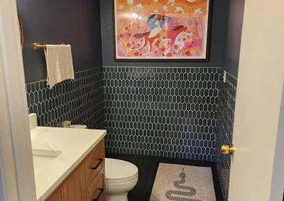 Seattle bathroom remodel featuring a modern vanity, hexagonal tile accent wall, unique artwork, and ambient LED lighting.
