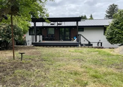Spacious modern patio with a covered pergola, black metal railing, and composite decking, extending from a contemporary home in Seattle. Built by expert patio and deck contractors in Seattle for comfort and style.