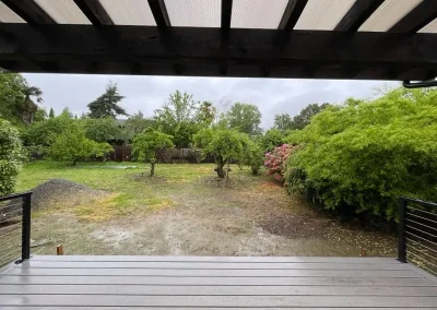 Modern covered patio with a pergola roof and composite decking, overlooking a lush green backyard in Seattle. Professionally built by leading patio contractors in Seattle for durability and outdoor enjoyment.