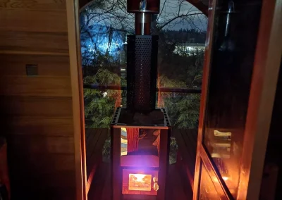 Seattle outdoor barrel sauna with a wood-burning stove glowing at night, creating a warm and relaxing ambiance.