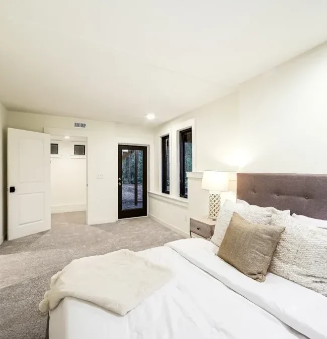 Home remodeling Seattle: Luxurious master bedroom transformation with plush bed, ensuite bathroom, soft carpeting, and modern design.