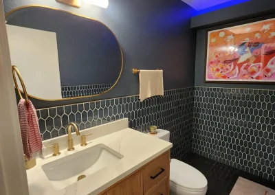 Seattle bathroom remodel featuring a modern vanity with a quartz countertop, gold fixtures, hexagonal tile backsplash, and accent lighting.