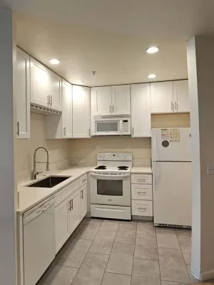 Compact kitchen remodel with white cabinetry, tile flooring, and modern lighting in a Seattle home renovation.