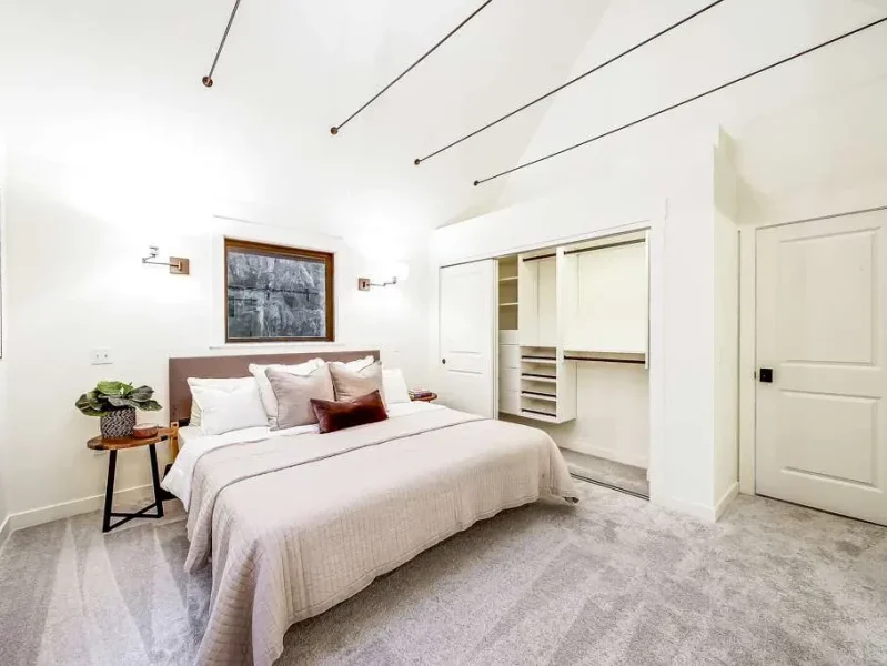 A modern white bathroom featuring a glass-enclosed shower with grey subway tiles, a pedestal sink, and a toilet, all in a clean, minimalist design.