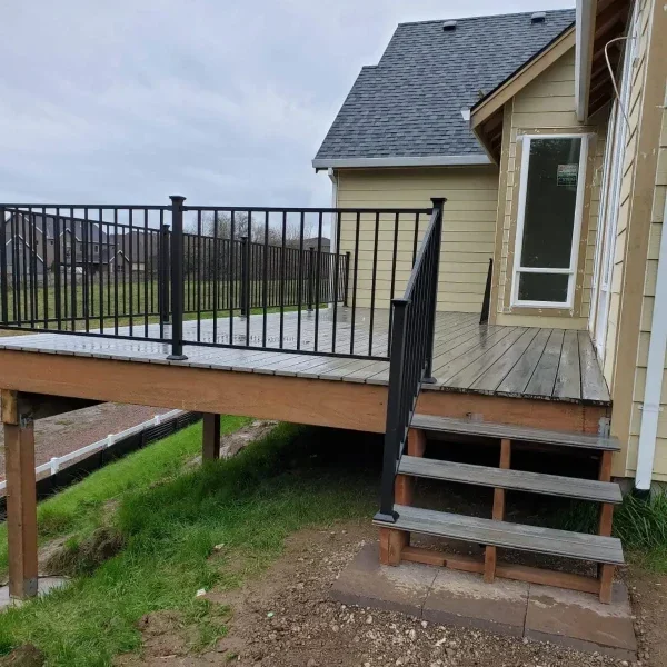 Custom-built elevated deck with black metal railing and wooden stairs leading to the backyard. Professionally constructed by leading deck builders in Seattle for enhanced outdoor living.