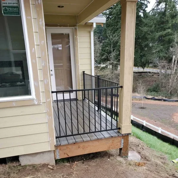 Seattle deck construction with black metal railing and siding installation in progress on a modern home.