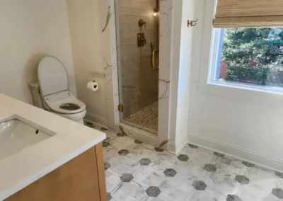 Master bathroom layout highlighting the intricate geometric marble floor tile and white oak vanity.