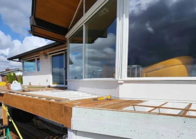 A residential deck under construction showing the exposed wooden floor joists and support framing.