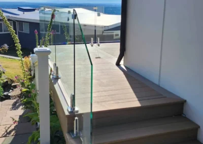Luxury composite deck stairs with frameless glass railings and stainless steel spigots.