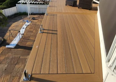 High-end composite deck with a diagonal board pattern, picture-frame border, and stainless steel glass railing hardware.
