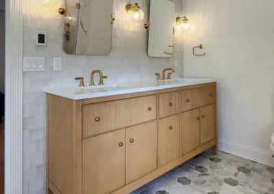 Side view of a wood bathroom vanity showing fluted textures and gold hardware.