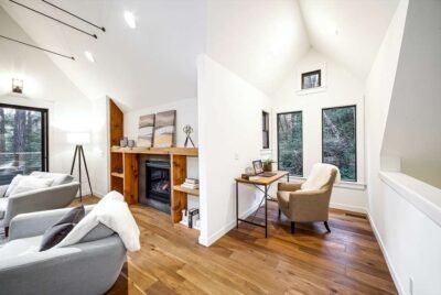 Full home remodeling A full house remodel with a cozy reading nook and a comfortable chair and a small desk, surrounded by large windows with forest views.