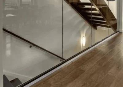 Architectural glass partition showcasing a modern wooden staircase and professional hardwood floor installation in an open-concept Seattle residence.