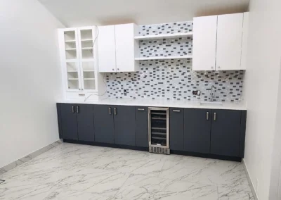 Kitchen corner with beverage station and dual-tone cabinets, wine fridge, and marble-veined tile flooring.