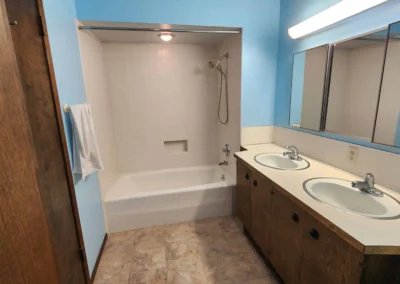 Original dated Mercer Island bathroom space prior to design-build transformation, featuring an outdated laminate double vanity, alcove tub, and vinyl flooring.