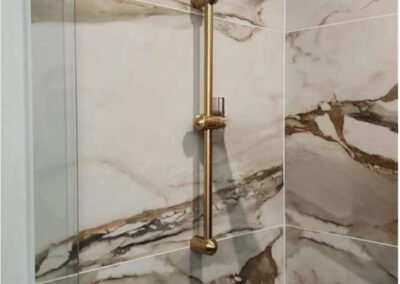 Tailored Mercer Island shower installation displaying premium brushed gold sliding hand shower hardware mounted against high-vein porcelain marble slab walls.