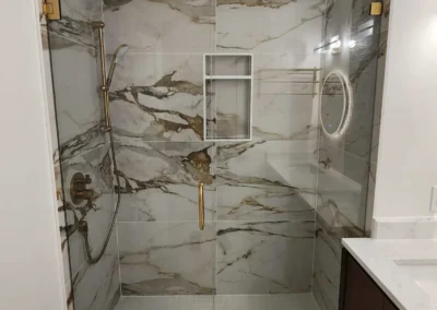 Tailored Mercer Island walk-in shower transformation featuring high-vein porcelain marble slabs, frameless glass enclosure, premium brushed gold hardware, and an integrated niche.
