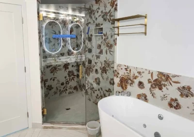 Custom Mercer Island primary bathroom execution featuring a freestanding soaking tub, frameless glass walk-in shower with patterned floral tile work, and chevron stone flooring.