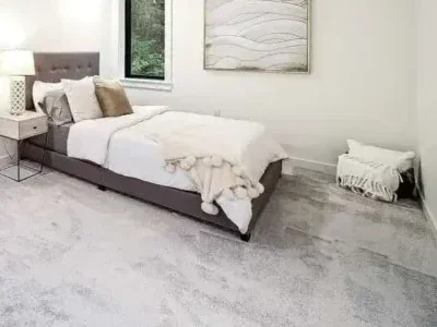 redmond-bedroom-remodel-plush-carpet-forest-windows Remodeled Redmond bedroom with new plush gray carpet, large black-framed windows overlooking forest, and a neutral decor palette