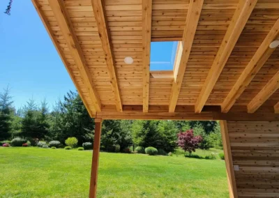 Underside of a cedar covered patio roof with exposed beams, a skylight, and support post over a stamped concrete patio in Redmond