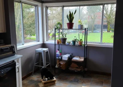 Original Redmond kitchen eating area before remodel with corner windows, dated tile floor, and a low dropped ceiling