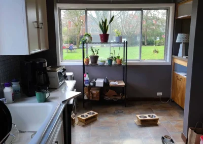 Original Redmond kitchen before remodel with a worn sink, laminate counters, and corner windows over a dated tile floor