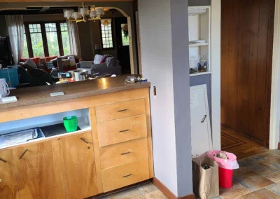 Original Redmond kitchen before remodel with a half-wall pass-through, dated wood cabinets, and tile flooring separating the kitchen from the living room