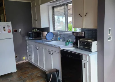 Original Redmond kitchen before remodel with cream cabinets, laminate counters, black dishwasher, and a dropped tile ceiling