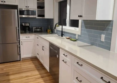 White cabinets, blue subway tile backsplash, and a stained wood beam in a Redmond kitchen remodel