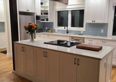 Taupe kitchen island with cooktop, flush ceiling hood, and wood beam in a Redmond kitchen remodel