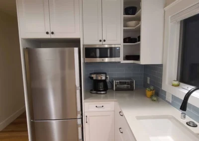 Stainless refrigerator framed by white cabinets with open corner shelves in a Redmond kitchen