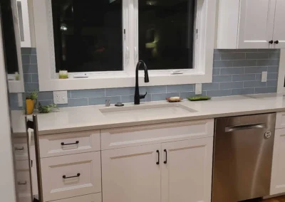 Undermount sink with matte black faucet below a window with blue tile backsplash in a Redmond kitchen