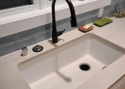 Undermount sink with matte black faucet below a window with blue tile backsplash in a Redmond kitchen