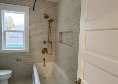 Freestanding soaking tub and brass shower with subway tile in a Kirkland bathroom remodel.