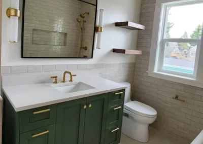 Green shaker vanity with a brass faucet and arched mirror in a Kirkland bathroom remodel.